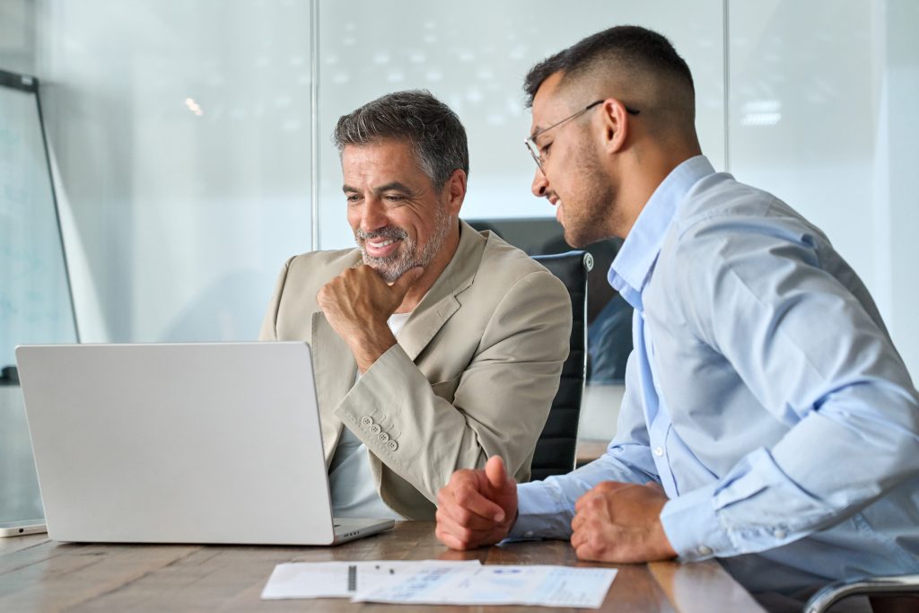 Two happy busy professional business men working using laptop in office. website development services